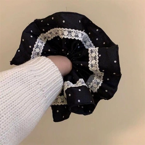 Detailed view of black polka dot hair scrunchie featuring elegant white lace trim