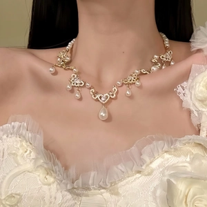 Vue détaillée d'un élégant collier de perles vintage avec cœur et goutte d'eau sur modèle.