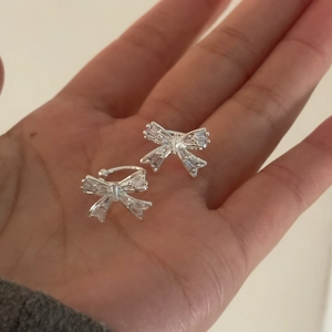 Gros plan détaillé d'un earcuff nœud en zircon étincelant tenu dans une main.