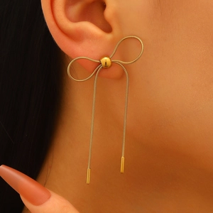 Close-up of golden bow tassel earrings on model featuring elegant snake chain detail