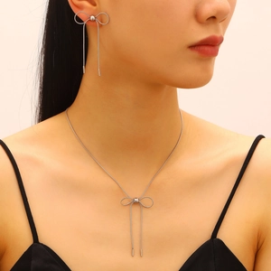 Close-up of a silver bow necklace and matching long tassel earrings on a model