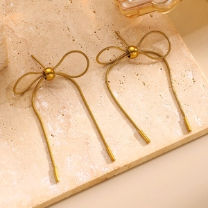 Detail von goldenen Schleifenohrringen mit Schlangenkettentabellen und Metallic-Finish