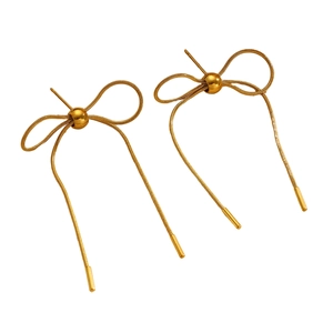 Detailed macro view of golden bow earrings with elegant long snake chain tassels