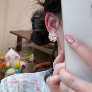 Close-up of an elegant large silver camellia flower stud earring worn on a person's ear