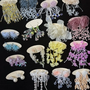 Various handmade floral acrylic and beaded drop earrings displayed on white cards