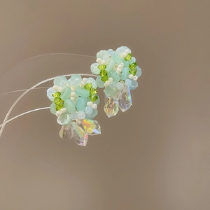 Detalle macro de pendientes de flores en acrílico verde menta y gotas de cristal