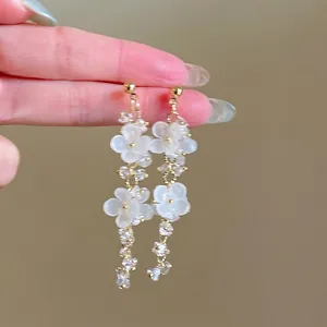 Close-up of elegant white acrylic flower drop earrings with shimmering crystal details