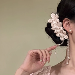 Close-up view of a pink silk flower hair clip with elegant dangling pearl tassels on hair