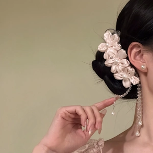 Close-up detail of pink fabric floral hair clip with elegant long pearl tassels on hair.