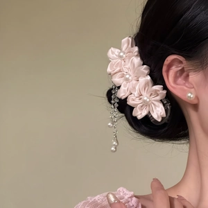 Side view of a model wearing a sweet pink fabric flower hair clip with pearl tassels
