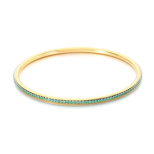 Eleganter Armreif aus goldfarbenem Titanstahl mit einer Reihe grüner Strasssteine
