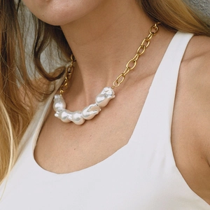 Détail d'un collier de perles baroques avec chaîne dorée porté par un mannequin