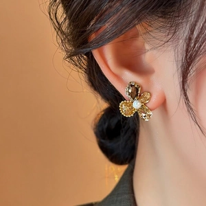 Detailed close-up of elegant gold-toned flower stud earrings with crystals and pearl