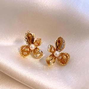Detailed view of elegant flower stud earrings featuring amber crystals and center pearl.