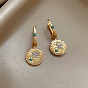 Macro view of vintage 18K gold plated earrings with star pattern and turquoise stones