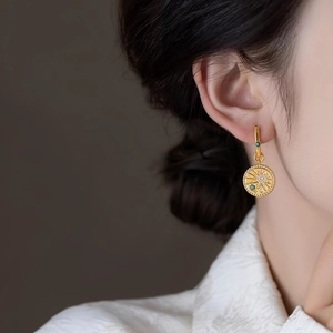 Close-up of vintage 18K gold plated round sunburst earrings with blue zircon detail.