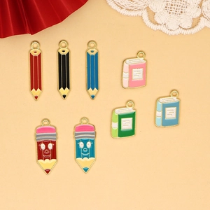 Detail view of colorful pencil and book alloy pendants for DIY graduation gifts.