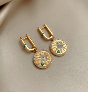 Close-up of 18K gold plated circular pendant earrings with starburst engraving and zircons.