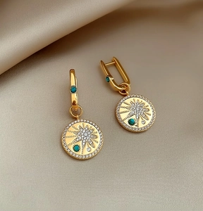 Detailed macro view of 18K gold plated hoop earrings with starburst zirconia pendant
