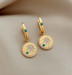 Close-up of vintage 18K gold plated zircon earrings with turquoise starburst details.