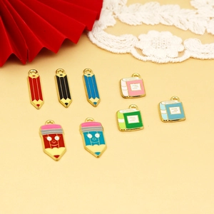 Detailed close-up of colorful enamel pencil and book pendants for graduation DIY jewelry
