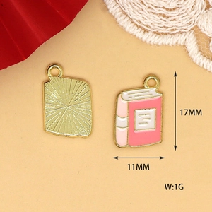 Detailed macro view of pink alloy book charm showing 17mm x 11mm size and weight.