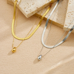 Close-up of double layered herringbone necklaces with polished teardrop pendants.