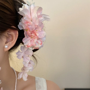 Elegant pink fabric flower hair clip with dangling floral tassels shown on a model side view.