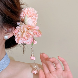 Close-up detail of a pink tulle fabric flower hair clip featuring elegant pearl tassels