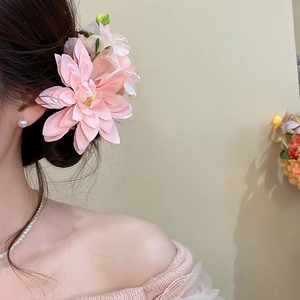 Detail of a soft pink fabric flower hair clip worn on a graceful updo hairstyle.