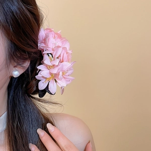 Detailed side view of an elegant pink fabric flower hair clip styled on long hair