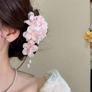 Close-up detail of a pink mesh flower hair clip with elegant pearl tassels on hair