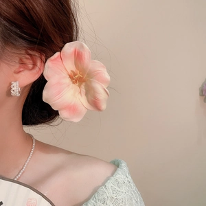 Detail of a sweet peach fabric flower hair clip worn by a model in an elegant style.