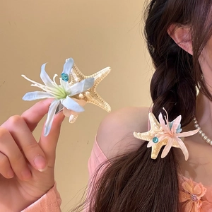 Vue détaillée de l'élégante pince à cheveux fleur en résille et étoile de mer sur tresse