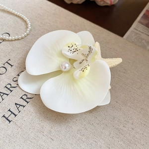 Elegant white orchid flower hair clip with pearl center on fabric background