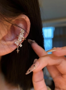 Detailed close-up of a sparkling geometric zircon star ear cuff worn on the ear