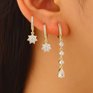 Detailed close-up of vintage gold flower and teardrop cubic zirconia earrings set on model's ear