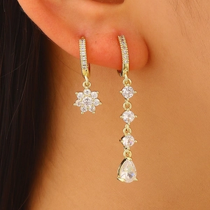 Close-up of elegant gold copper earrings with sparkling zircon flower and drop pendants.