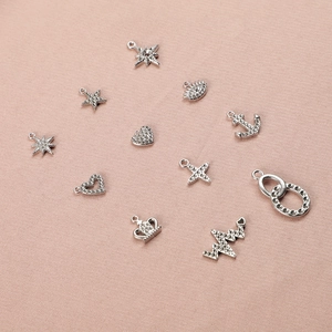 High-quality detailed macro view of silver zircon charms in various shapes on pink fabric