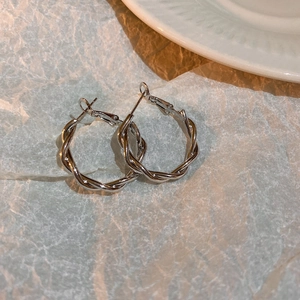 Detailed view of minimalist silver twisted hoop earrings with elegant metallic texture