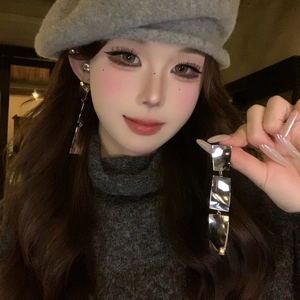 Gros plan de boucles d'oreilles métalliques argentées sur un mannequin asiatique.