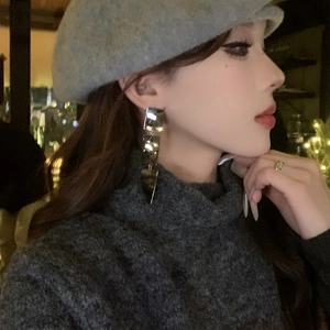 Gros plan d'un mannequin portant des boucles d'oreilles métalliques de style rétro chic