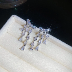 Gros plan de boucles d'oreilles pendantes en zircon avec pierres en poire en écrin blanc.