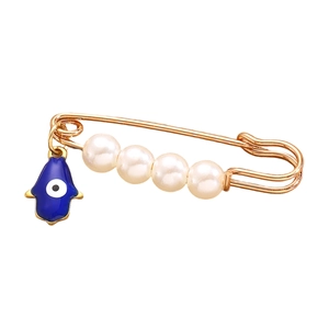 Dettaglio spilla dorata con perle bianche e ciondolo Mano di Fatima con occhio blu