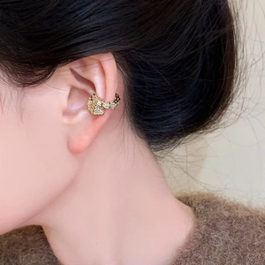 Detailed view of a golden snake ear cuff with sparkling zircons worn on the auricle