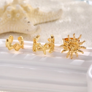 Detailed view of gold starfish shell and sun ear cuffs on a white textured stand