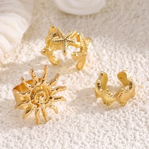 Detail of golden sun and starfish jewelry pieces on white textured beach sand