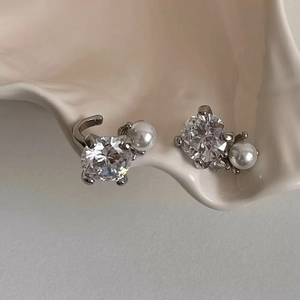 Macro view of elegant silver-tone ear cuffs featuring brilliant zircons and white pearls