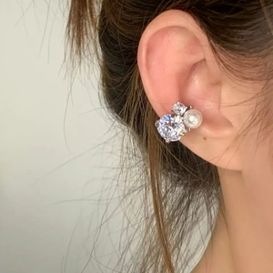 Macro detail showing a sparkling zircon and pearl ear cuff worn on a non-pierced ear.
