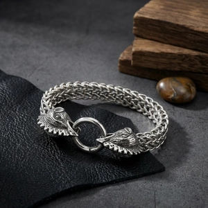 Close-up of double wolf heads biting a metal ring on a braided steel bracelet